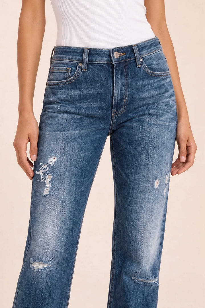 Close-up detail of distressed fabric texture on dark blue wide-leg jeans