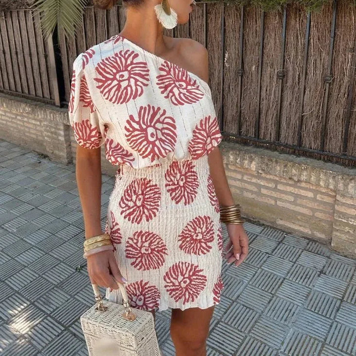 Woman facing forward in a white one-shoulder floral mini dress