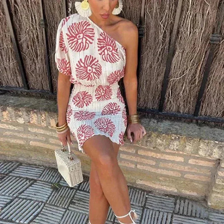 Woman in a three-quarter turn wearing a white one-shoulder floral mini dress