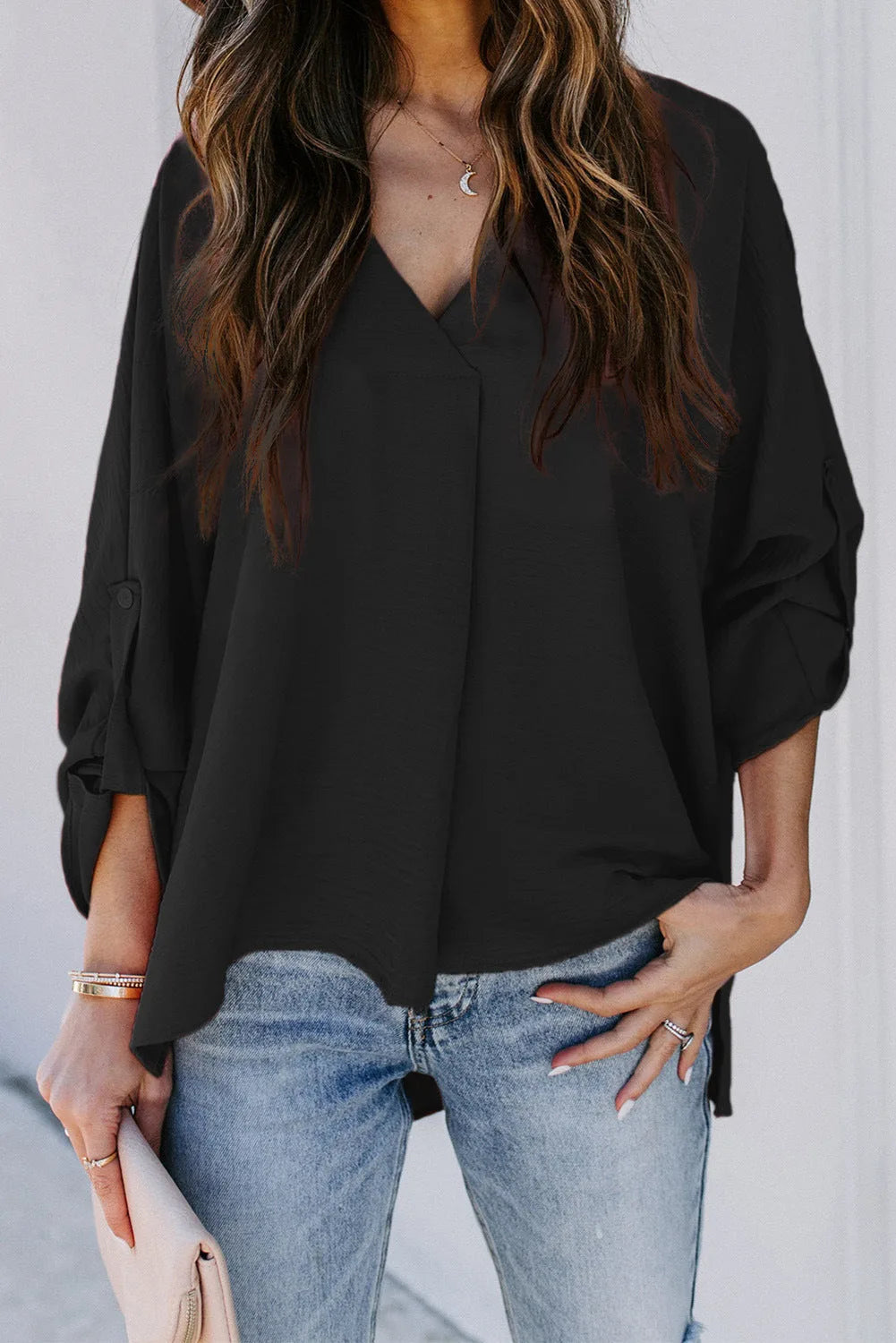 Black v-neck cuffed blouse, model shown from the side