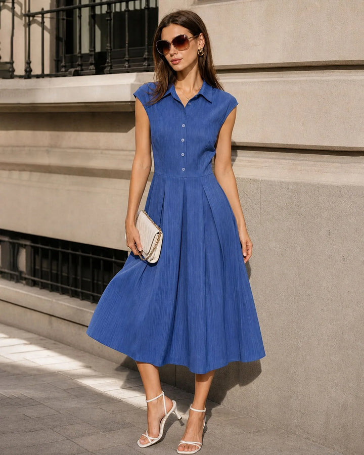 Model in side profile wearing a blue pleated midi dress highlighting the silhouette