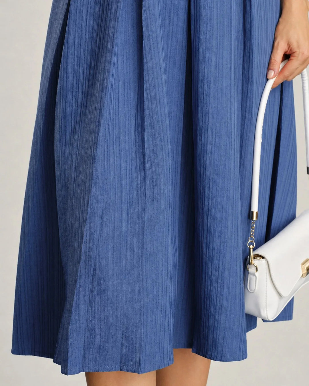 Model at a three-quarter turn in a blue pleated midi dress showing skirt movement