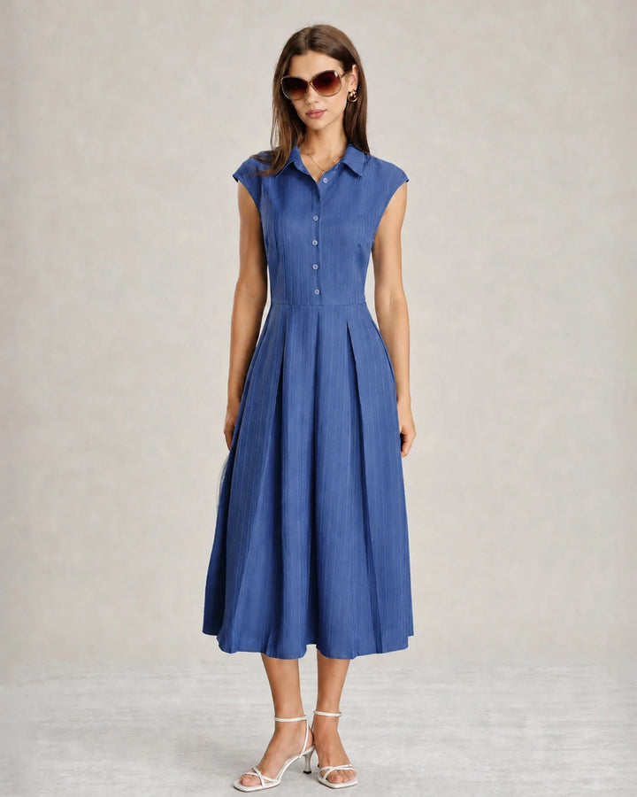 Model wearing a blue pleated midi dress in a relaxed standing pose