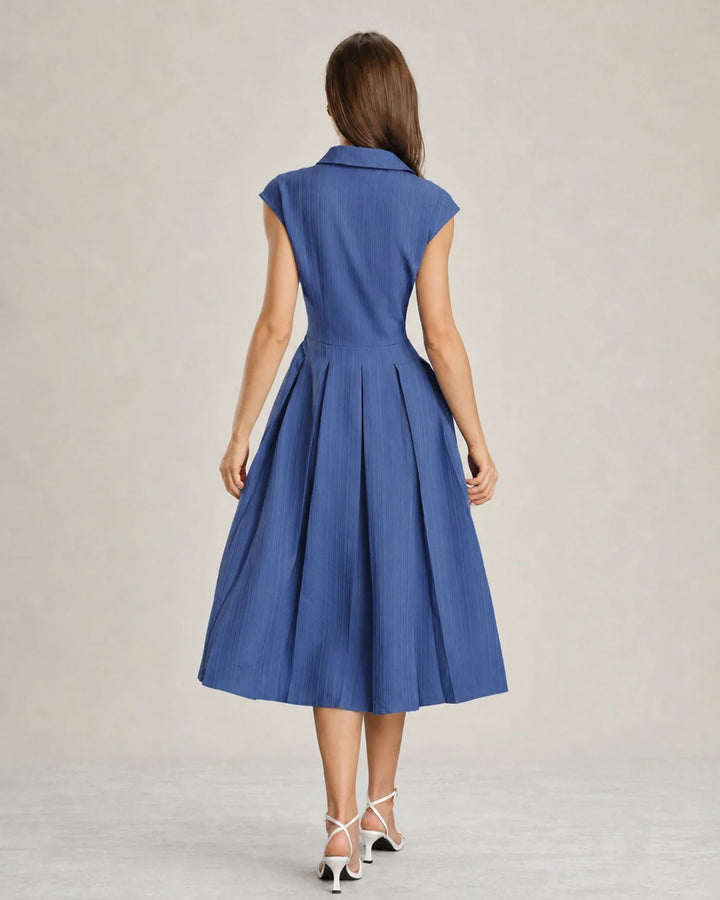 Model in a blue pleated midi dress shown from an alternate angle