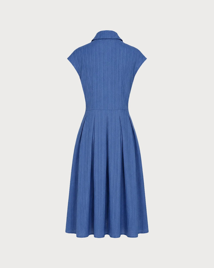 Model posing in a blue pleated midi dress with skirt drape visible