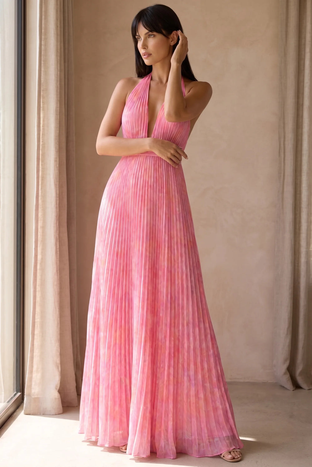 Model wearing pink pleated halter gown in lifestyle setting