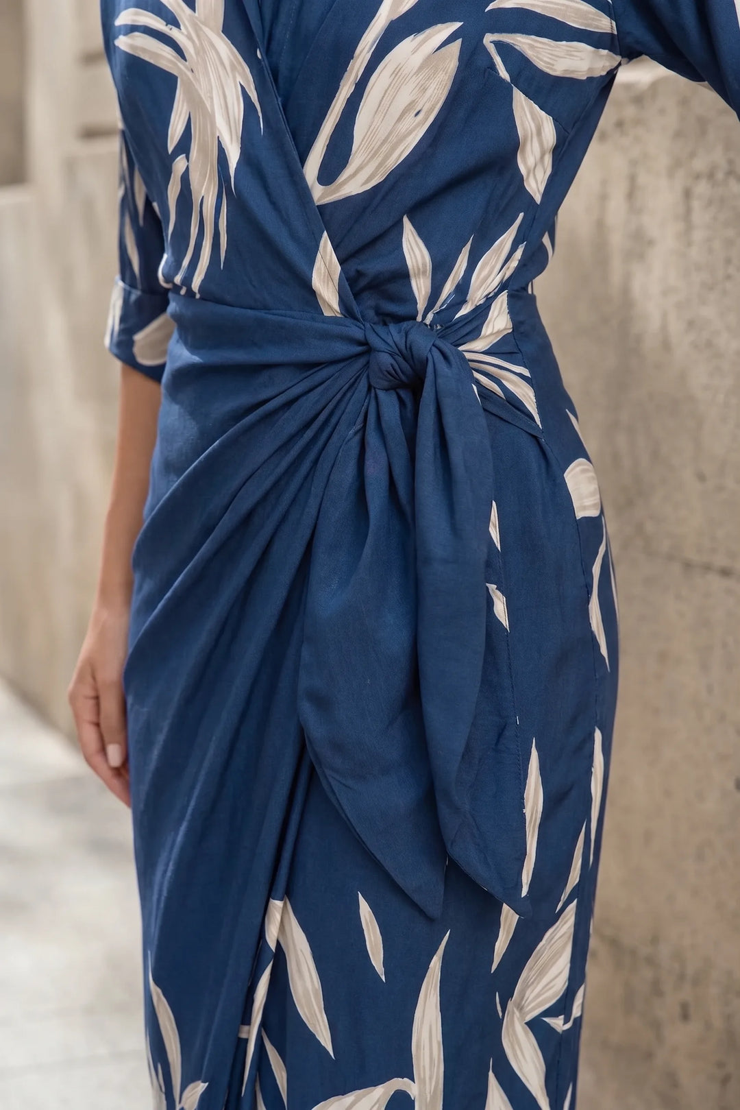 Close-up detail of blue wrap knot maxi dress fabric and knot tie