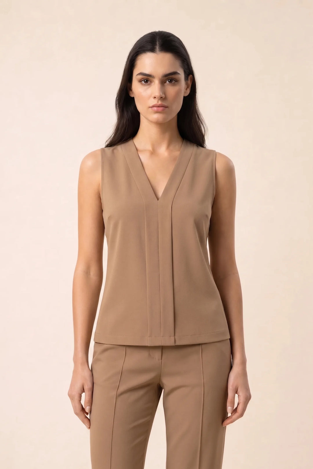 Beige v-neck blouse with centre pleat detail, model in contrapposto stance