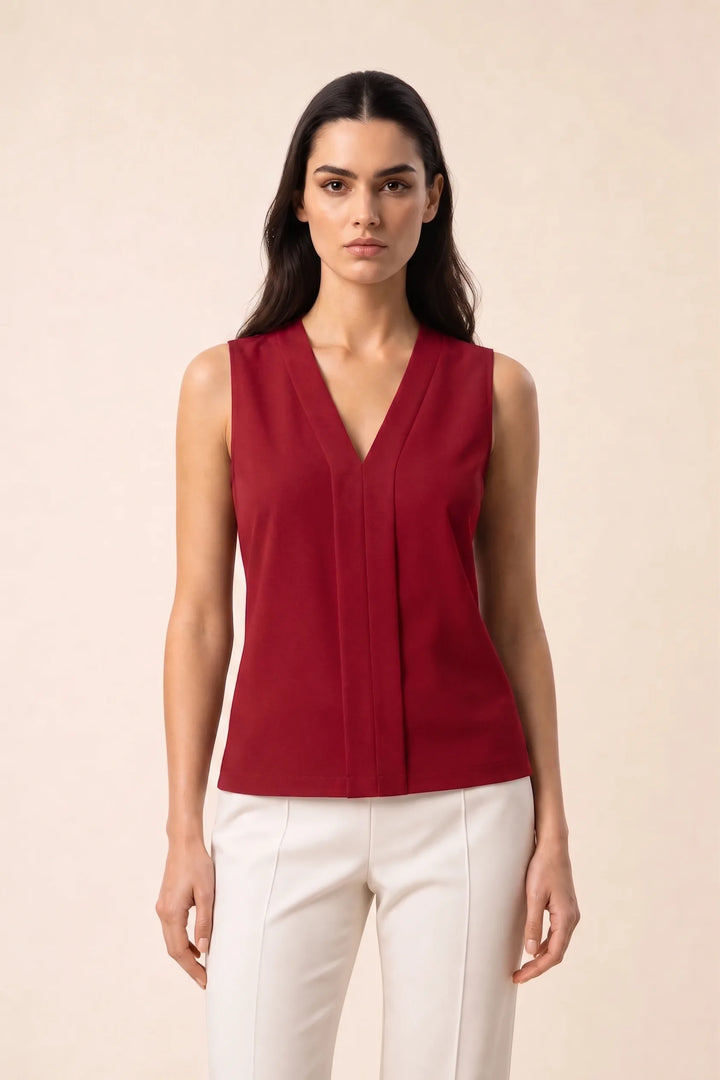 Red v-neck blouse with centre pleat detail, model in contrapposto stance