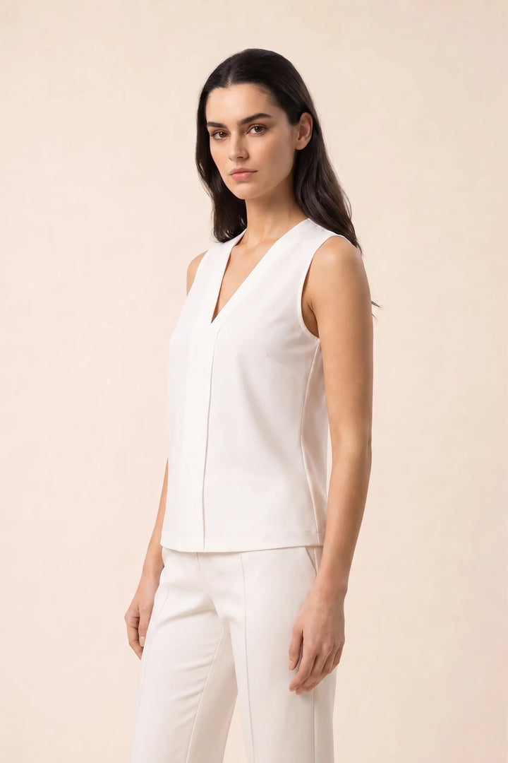 White v-neck blouse with centre pleat detail, model in three-quarter turn