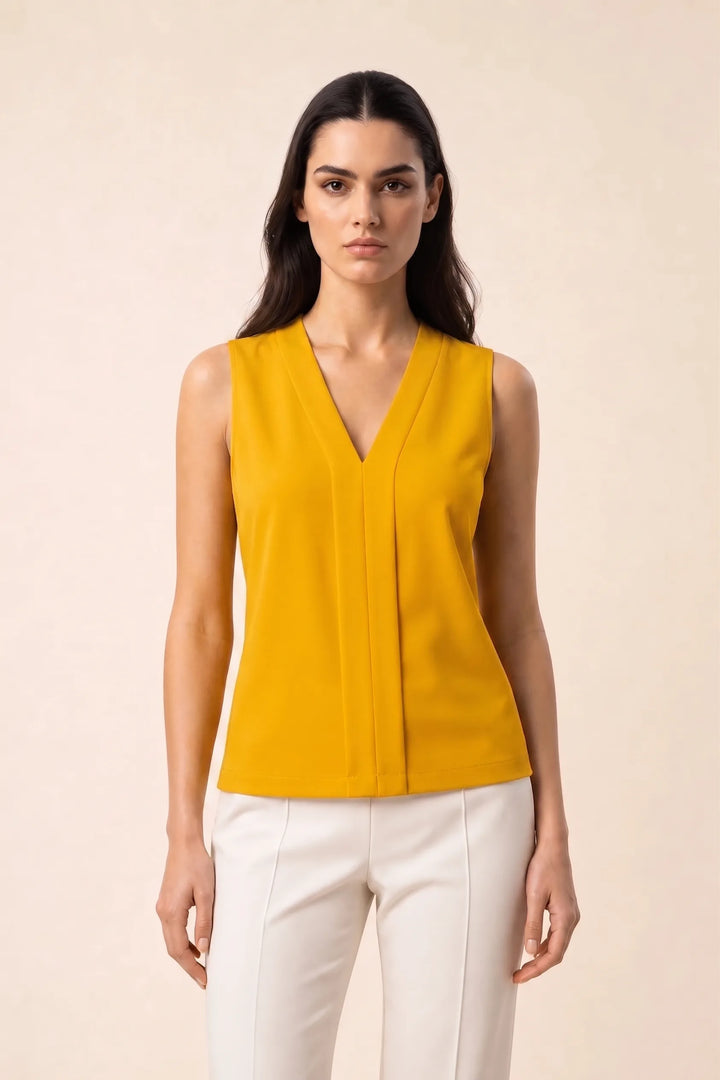 Yellow v-neck blouse with centre pleat detail, model in contrapposto stance