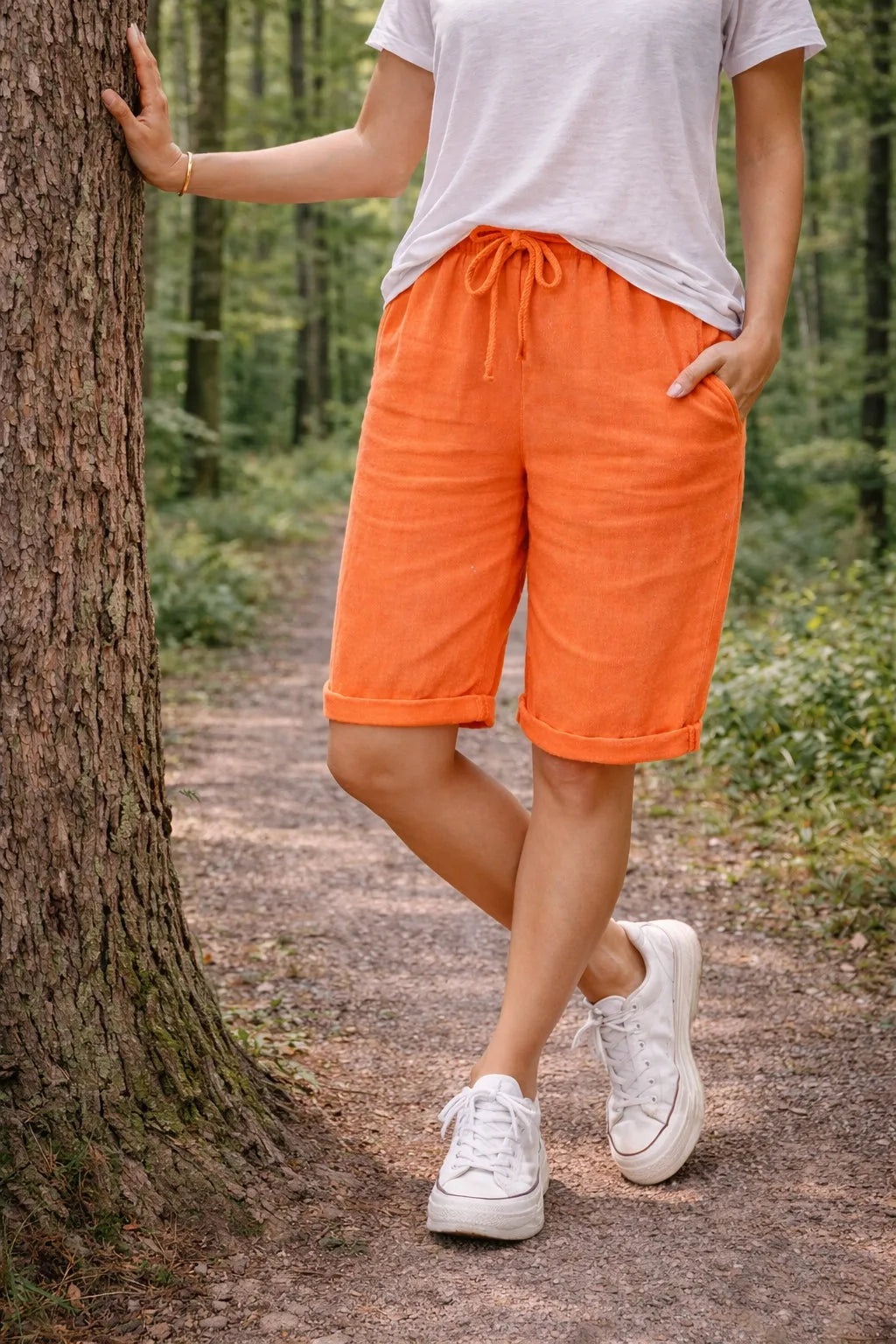 Orange drawstring Bermuda shorts on model, three-quarter turn
