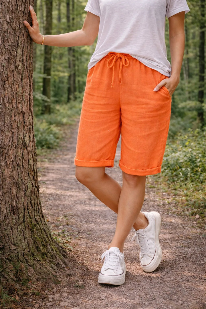Orange drawstring Bermuda shorts on model, three-quarter turn