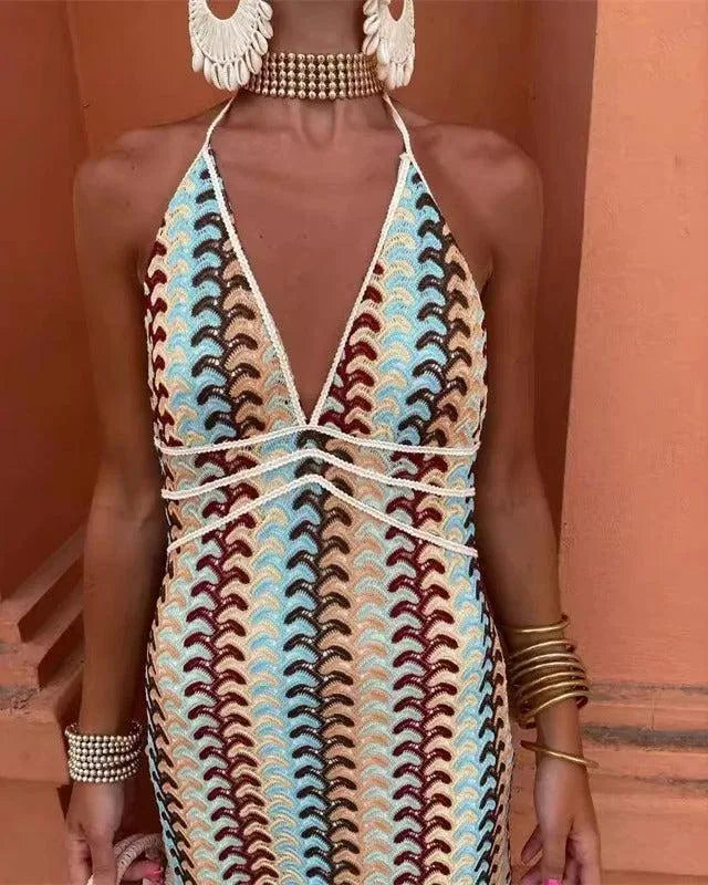 Woman in a beige multicolor crochet halter maxi dress, turned three-quarters to camera