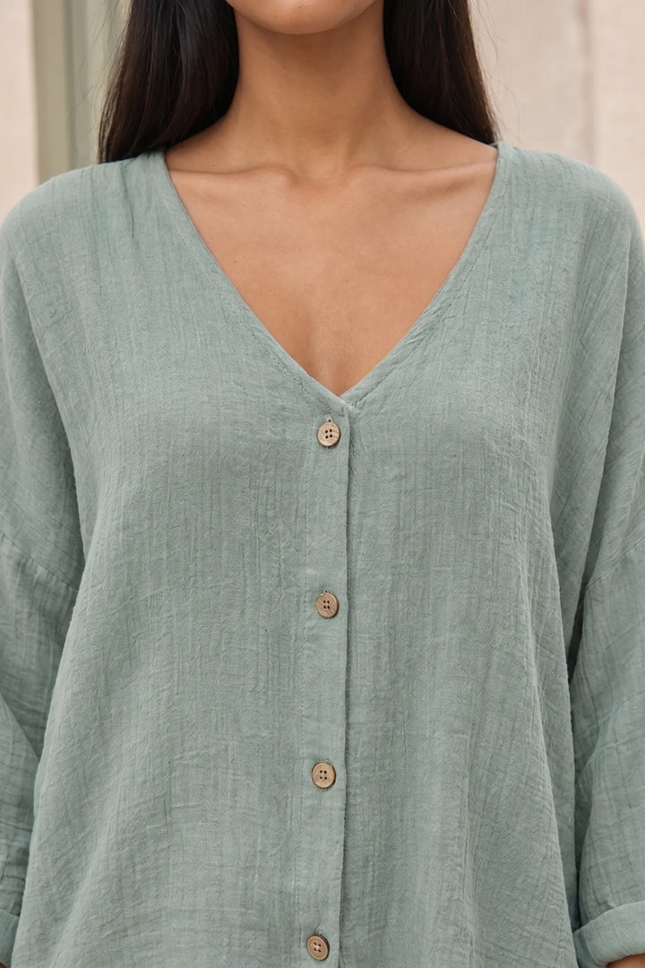 Close-up detail of a green button-front relaxed blouse showing fabric and buttons