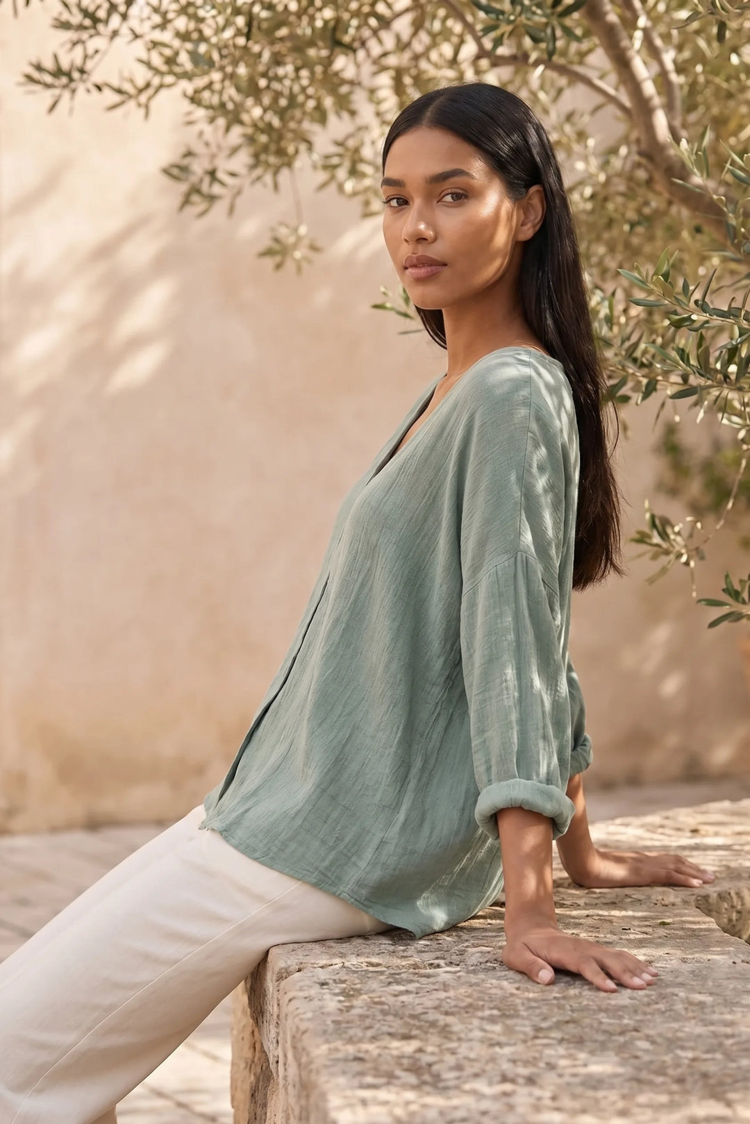 Model wearing a green button-front relaxed blouse in an outdoor lifestyle setting