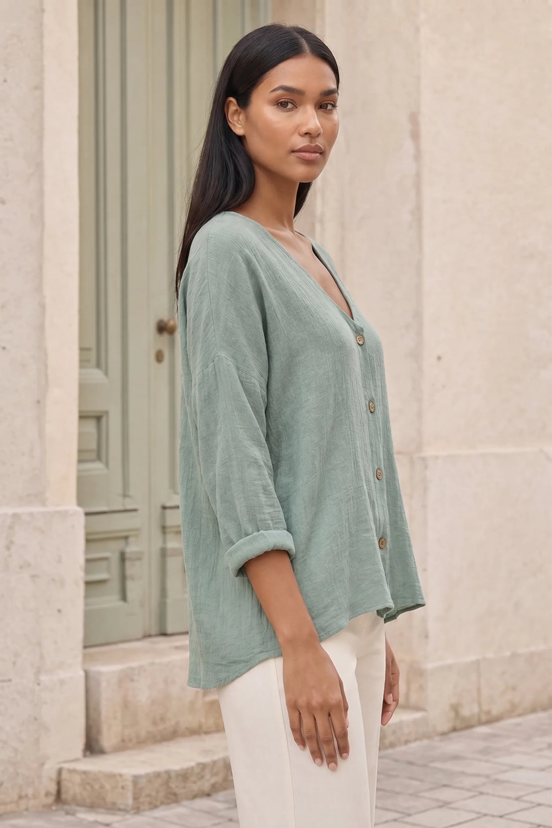 Model wearing a green button-front relaxed blouse in a three-quarter turn