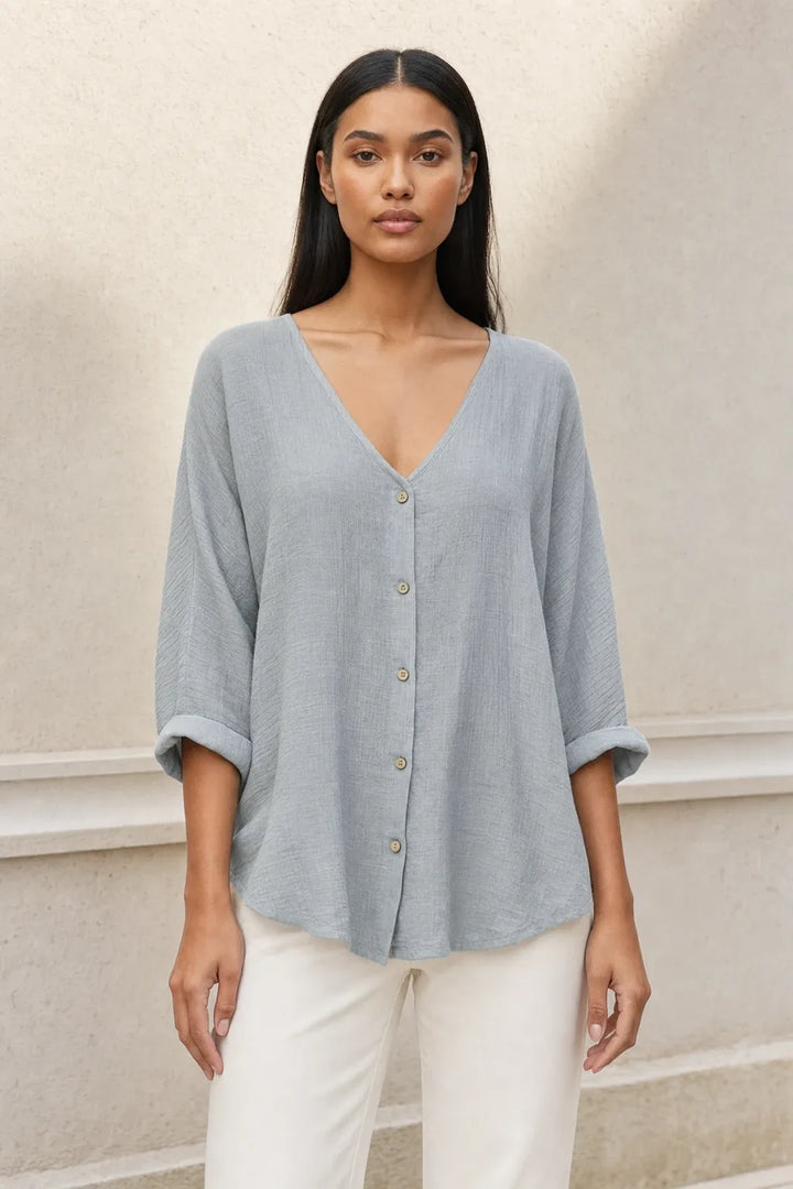 Model in a grey button-front relaxed blouse, standing in a contrapposto pose