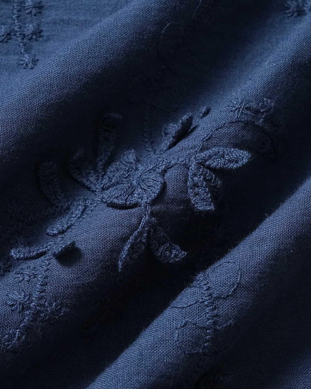 Close-up detail of lace trim and embroidery on a blue blouse