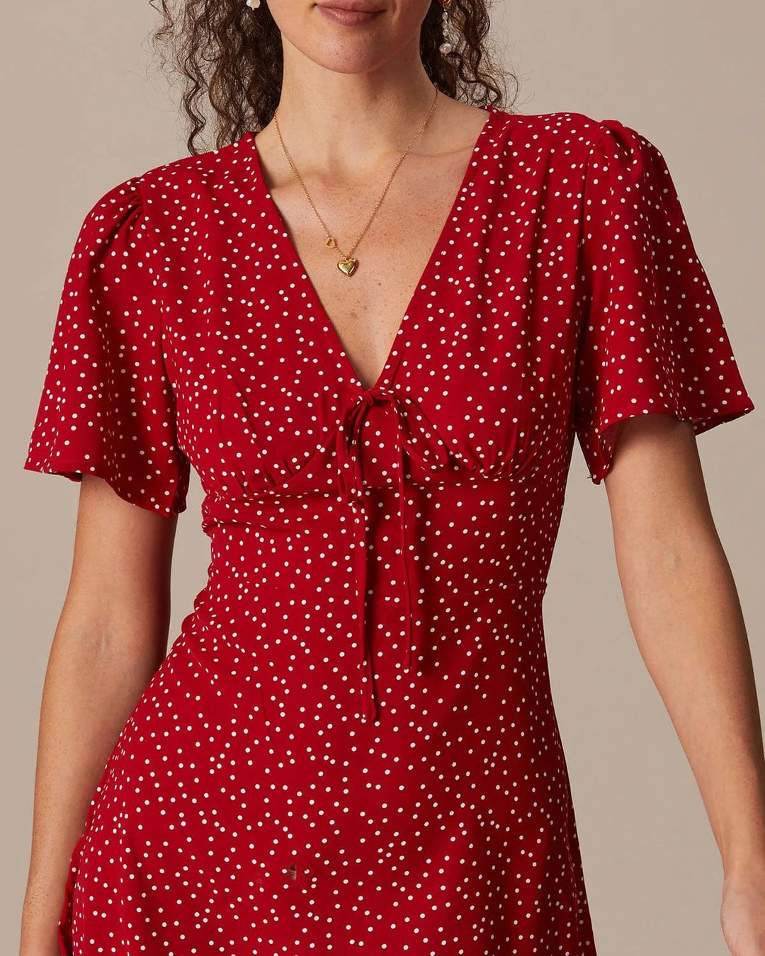 Model at a three-quarter turn in a red tie-front mini dress showing silhouette and knot