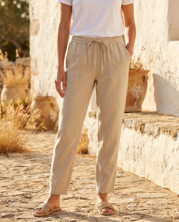 Beige drawstring tapered pants on model facing forward, relaxed fit with tapered ankles
