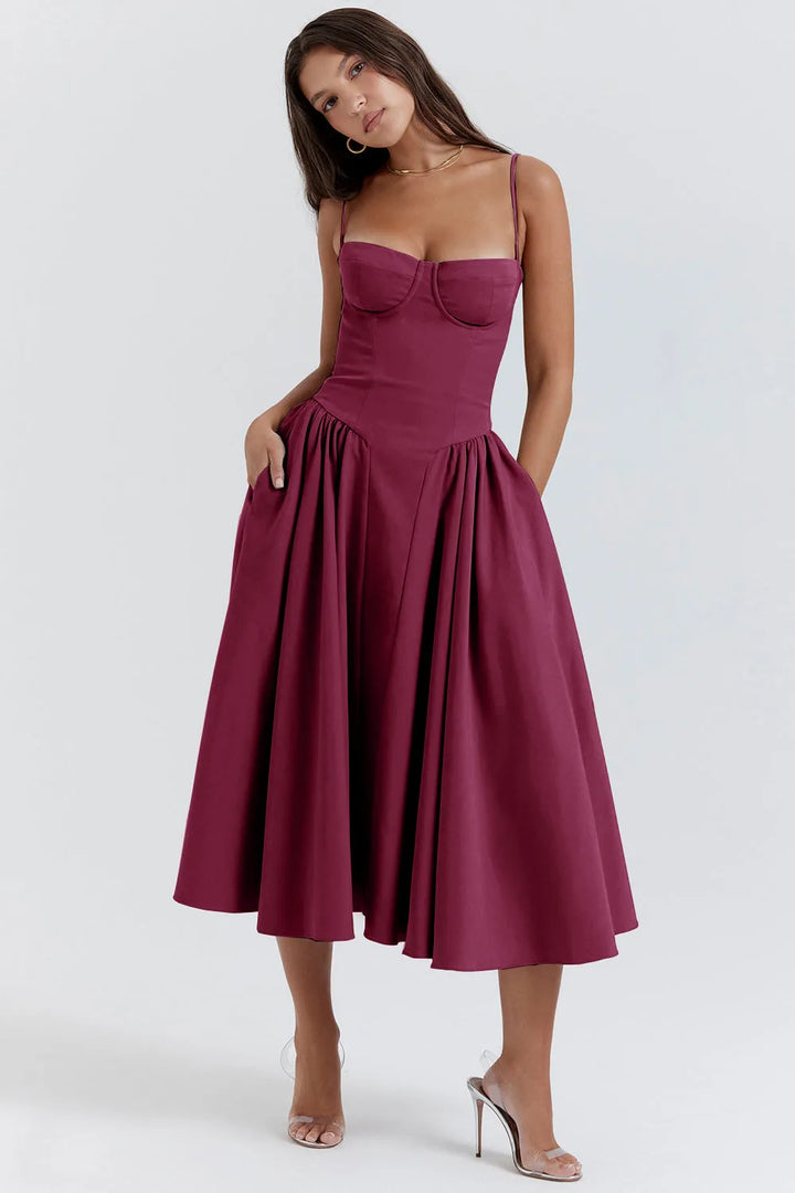 Model wearing a plum red corset midi dress with structured bodice and flowing midi skirt