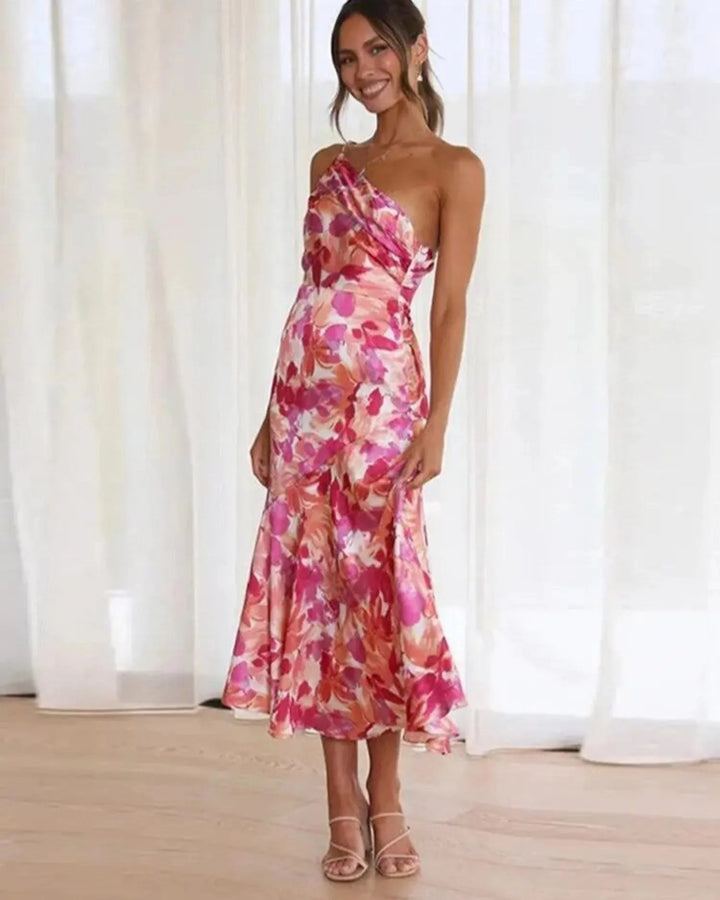 Model in a three-quarter turn wearing an orange floral one-shoulder midi dress