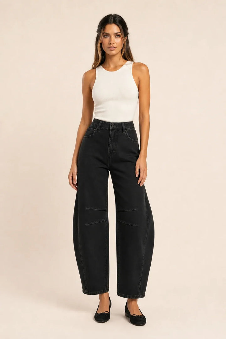 Black barrel leg jeans on a model standing in a contrapposto pose