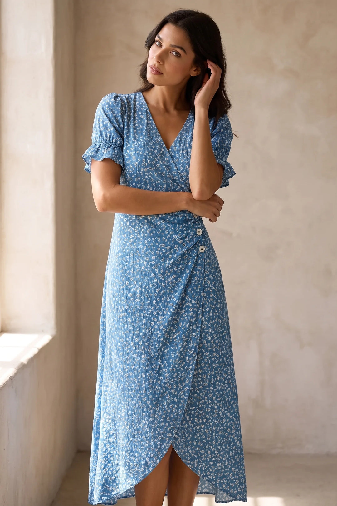 Model wearing blue flutter sleeve wrap midi dress in lifestyle setting