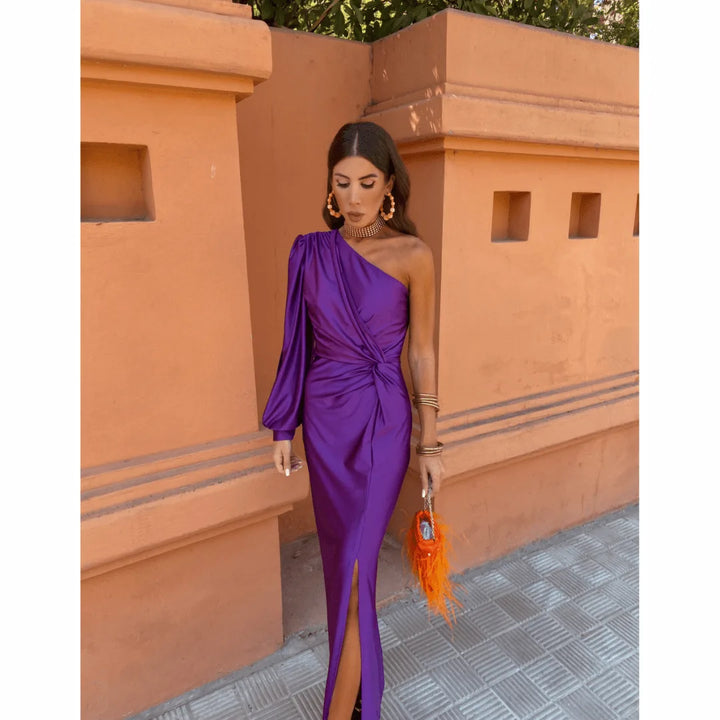Woman in a lavender one-shoulder twist maxi dress, turned three-quarters to show silhouette