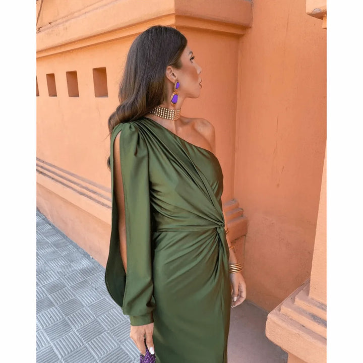 Side view of a woman wearing an olive green one-shoulder twist maxi dress