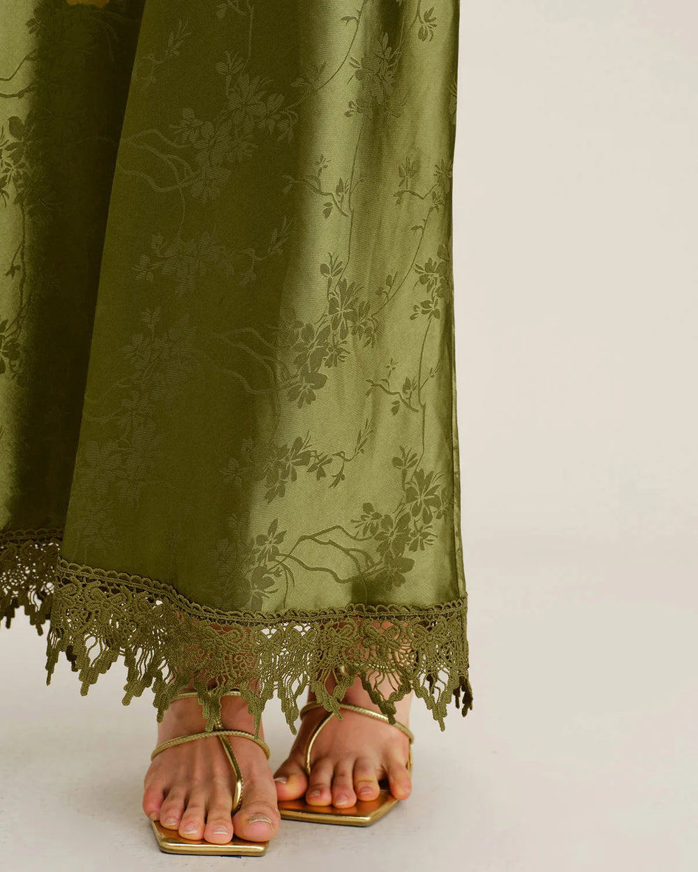 Close-up detail of lace-up bodice and jacquard texture on a green maxi dress