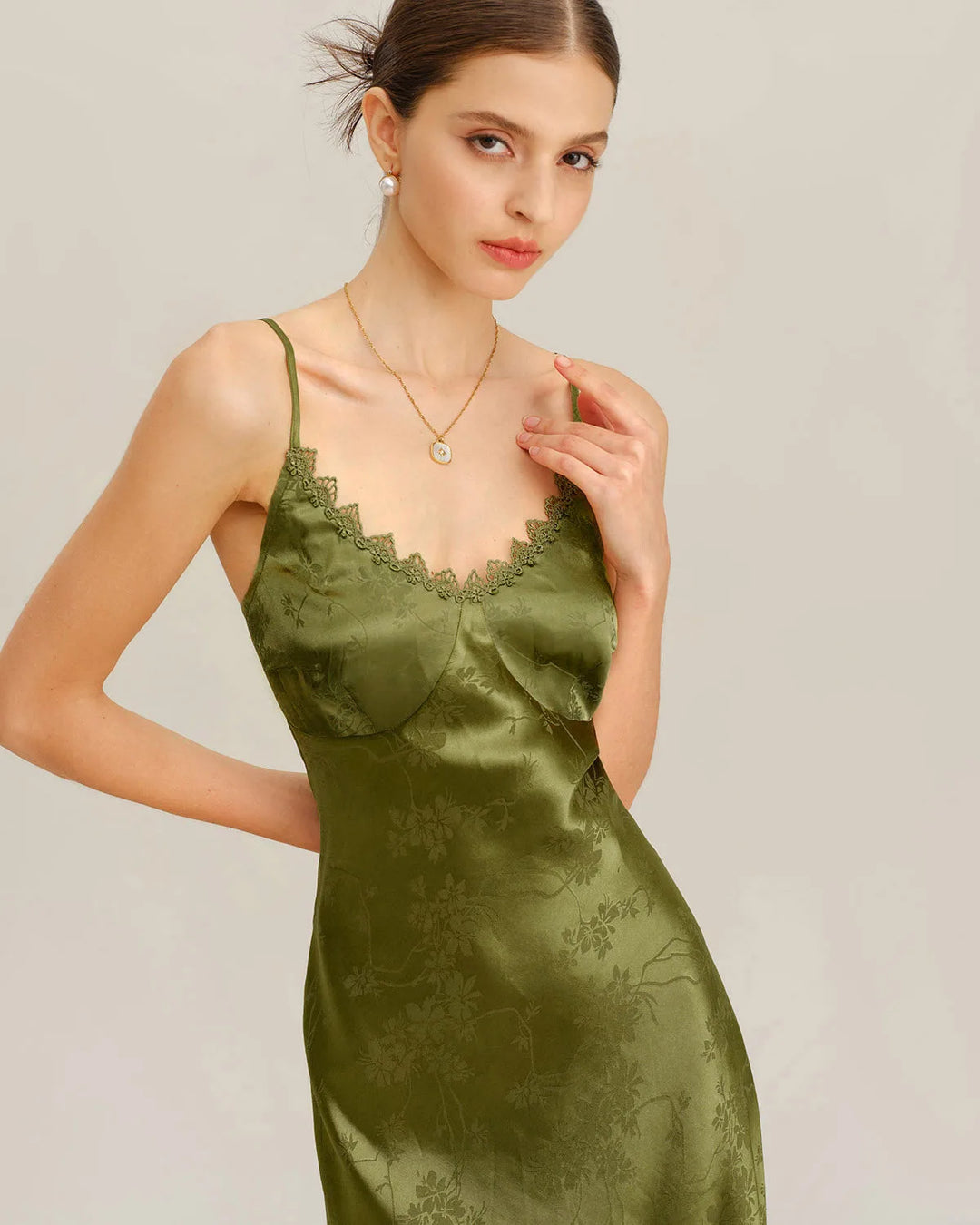 Model in a three-quarter turn showing green jacquard maxi dress with lace-up bodice