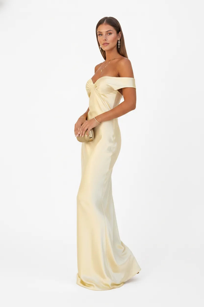 Woman in a yellow off-shoulder satin gown shown from a three-quarter angle