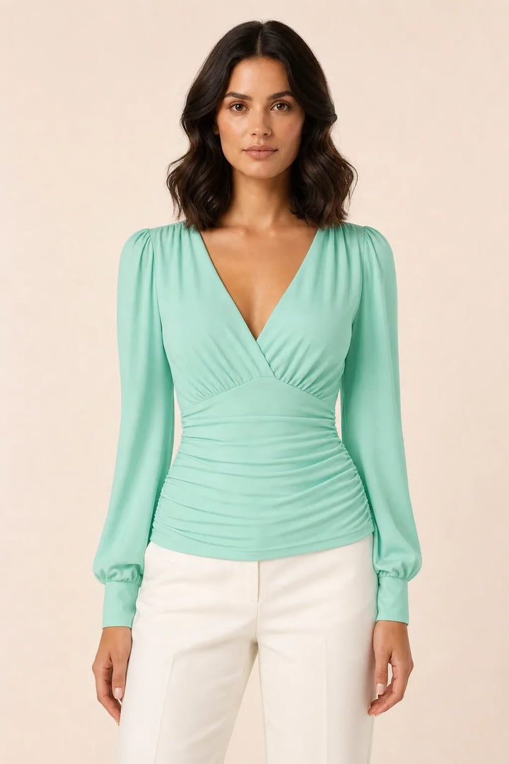 Light green ruched wrap blouse on model in contrapposto stance, v-neckline and gathered waist