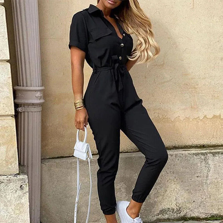 Model in side pose wearing a black striped belted jumpsuit