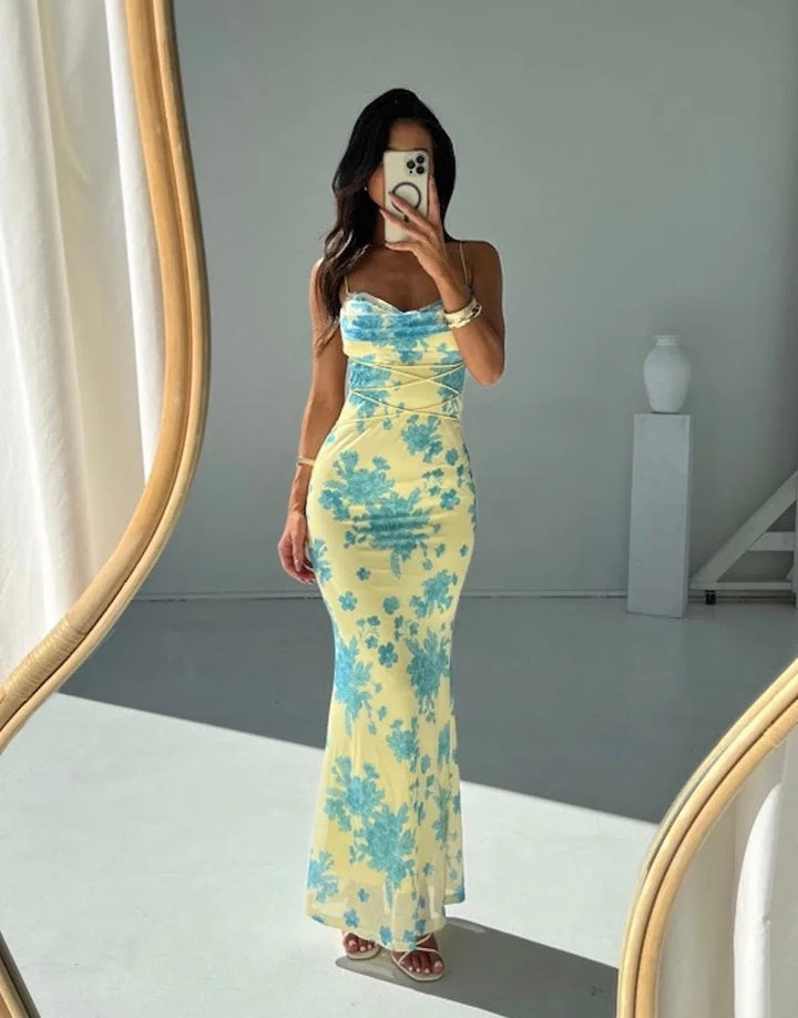 Side view of a woman in a yellow and blue floral maxi dress with lace-up detail