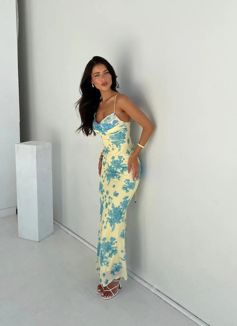 Woman in a yellow and blue floral lace-up maxi dress, turned at a three-quarter angle