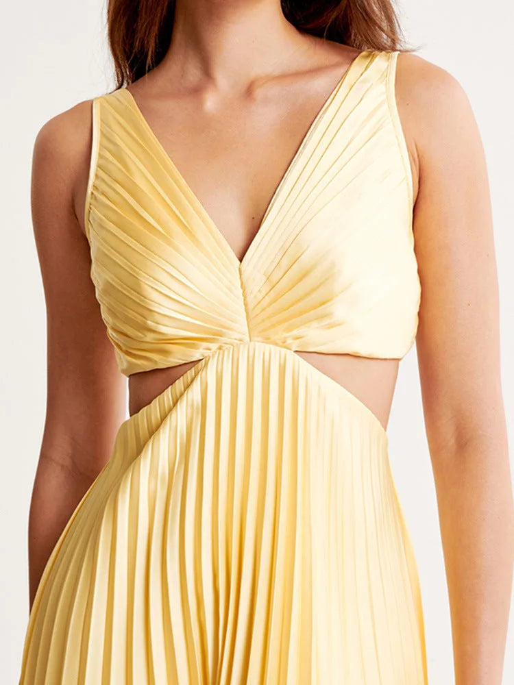 Woman styled in a yellow pleated cutout midi dress, full-length view