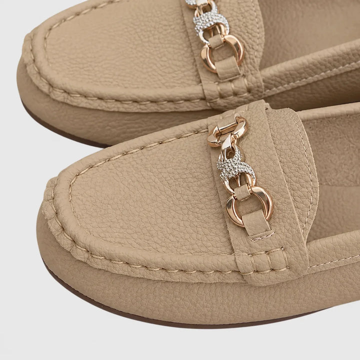 Close-up detail of chain embellishment on white loafer