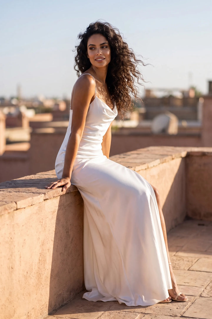 Model wearing white cowl neck backless gown in outdoor lifestyle setting