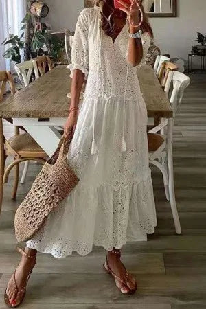 Close-up detail of white boho maxi dress showing tassel trim and fabric texture