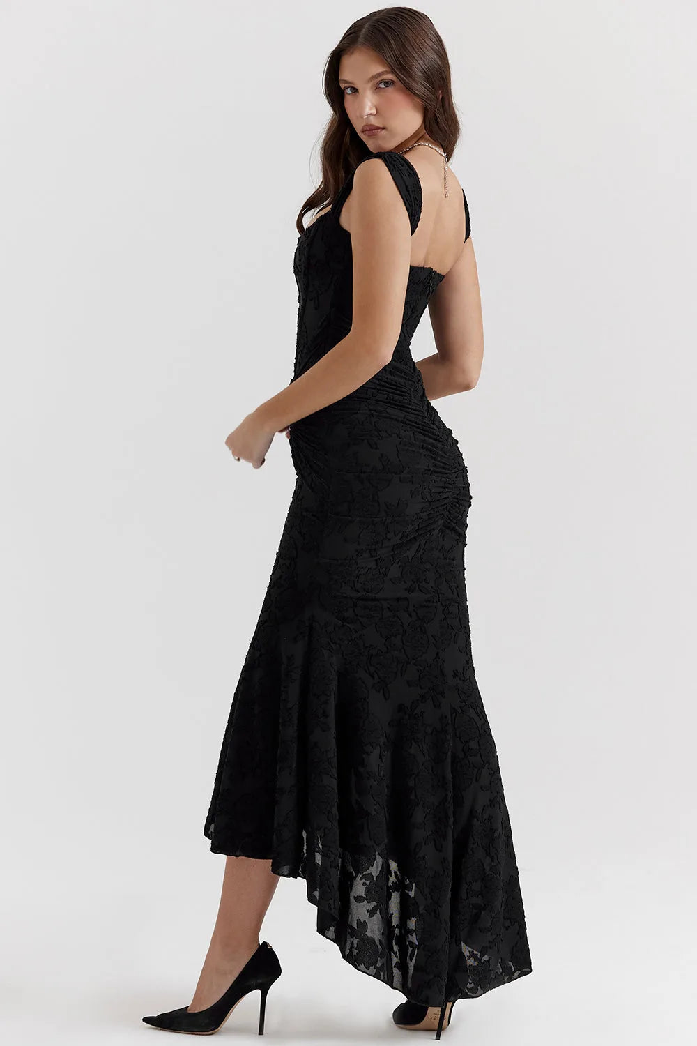 Model in a three-quarter turn wearing a pink lace mermaid gown with a trailing skirt