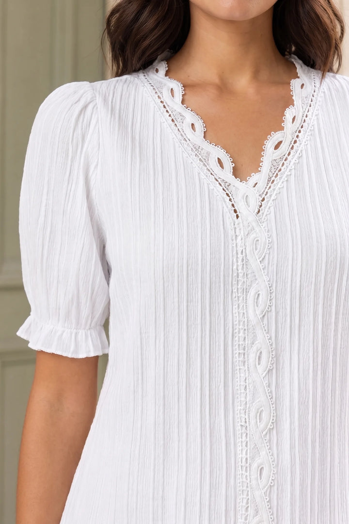 Close-up detail of lace trim and puff sleeve on a light tan blouse