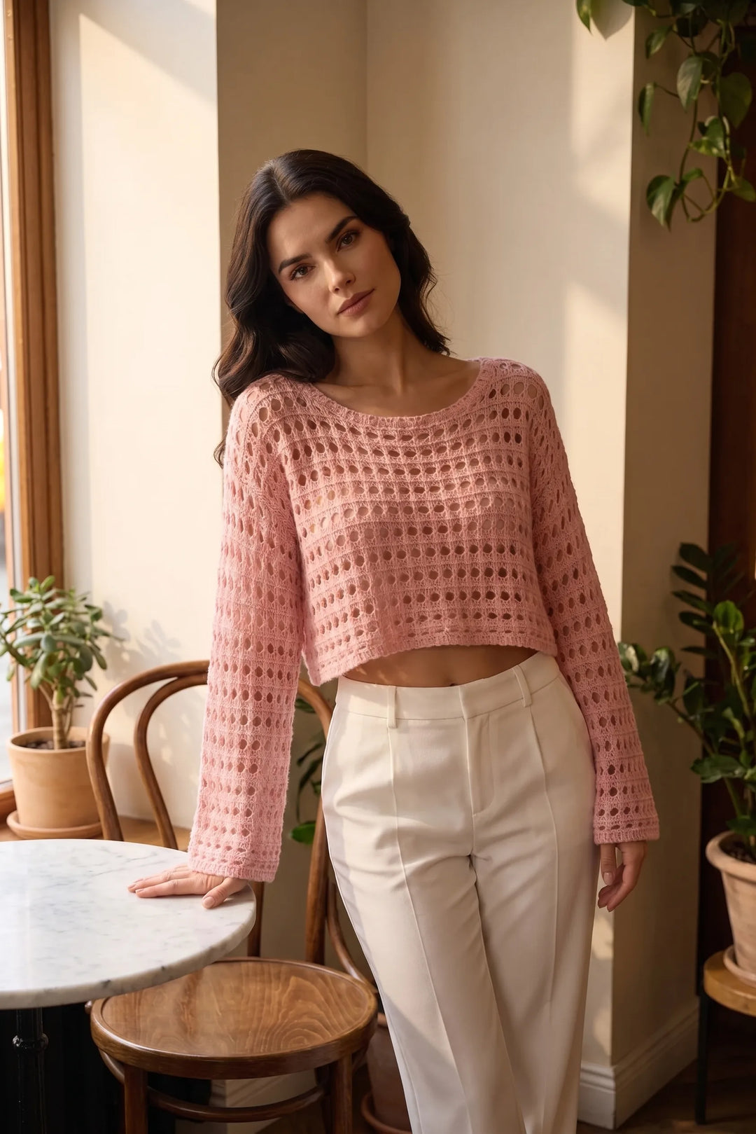Model wearing pink open knit crop top in a lifestyle setting