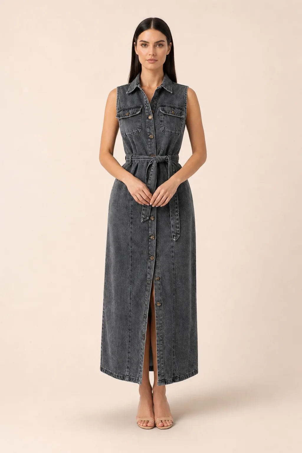 Woman in a belted black denim maxi dress standing in a contrapposto pose