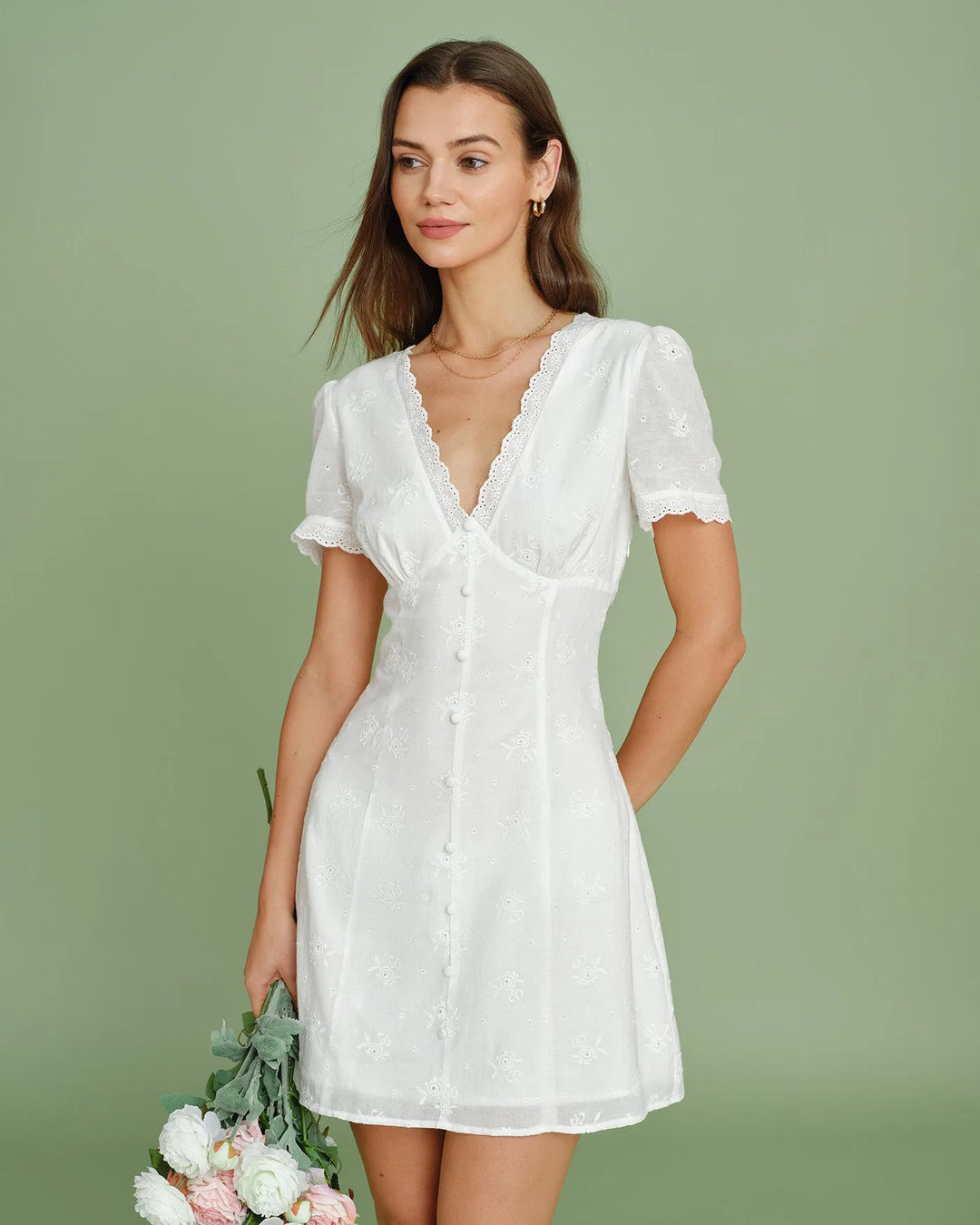 Close-up of white eyelet fabric and button detail on mini skirt