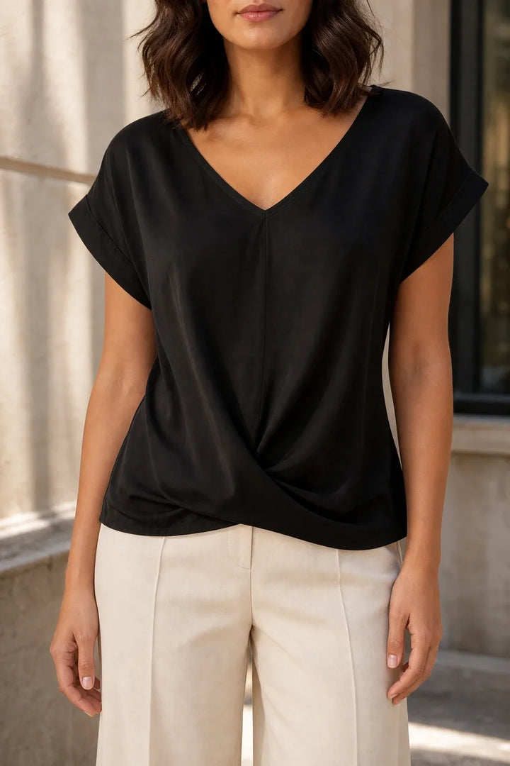 Black twist-front sleeveless top on model in contrapposto stance