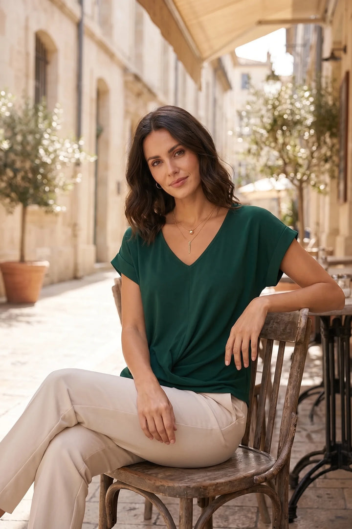 Model wearing green twist-front sleeveless top in outdoor lifestyle setting