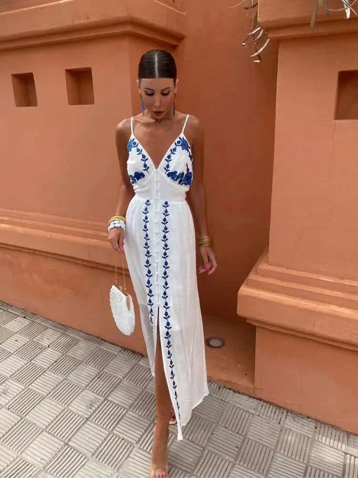 Woman facing forward in a white embroidered maxi dress with long sleeves and floral detailing